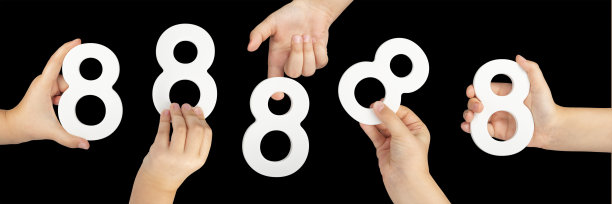 8号手握，黑色背景。一个孩子手里拿着黑色背景的数字8。“八”字:用数字“八”来插入一个项目或设计的一双手图片下载
