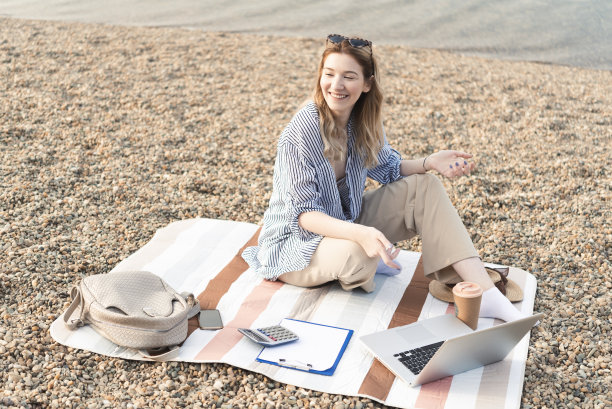 一个快乐的年轻女子的肖像从海滩上工作和享受图片下载