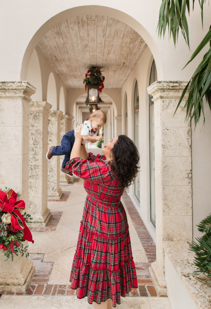 2022年12月，一位年轻的母亲快乐地抱着她10个月大的儿子，穿着喜庆的红色圣诞格子呢套装，拍摄家庭圣诞照片图片下载