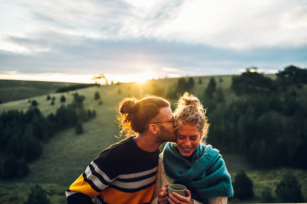 日出时，年轻夫妇站在阳台上喝咖啡或茶图片下载
