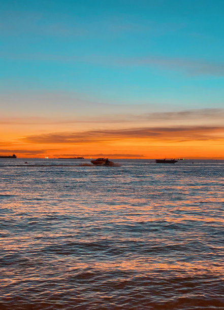 海景，海上的船只在美丽的日落，阳光反射在水面上图片下载
