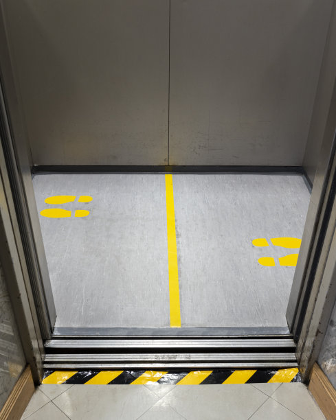 公共电梯内黄色脚印标志为COVID-19保持社交距离图片下载