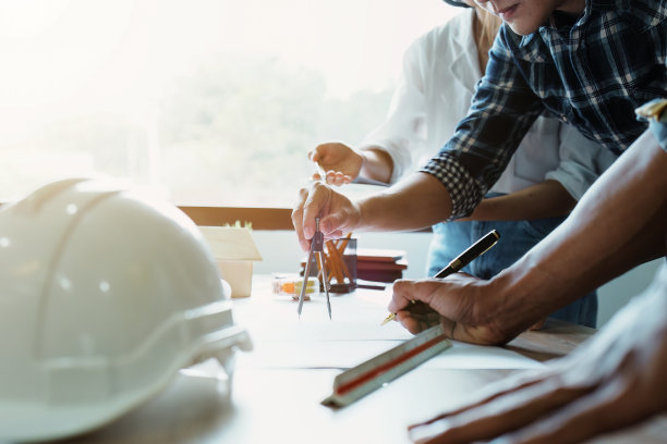 工程师们正在咨询团队，为客户设计一个建筑结构，有蓝图和建筑模型，可以在办公室工作图片下载