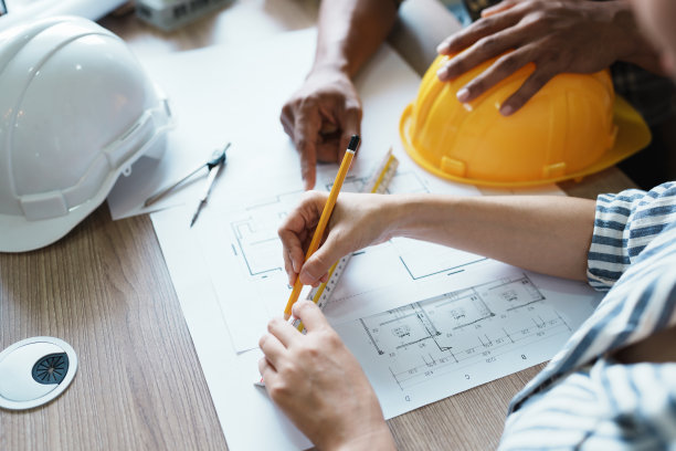 工程师们正在咨询团队，为客户设计一个建筑结构，有蓝图和建筑模型，可以在办公室工作图片下载