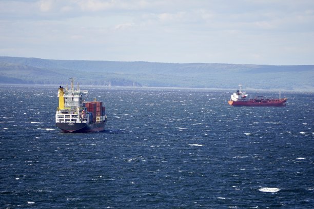 在晴朗的天气里，波涛汹涌的大海。湛蓝的天空上有云，海上有船只和帆板运动员。海上的风。风帆冲浪者在湛蓝的天空下乘风破浪。图片下载