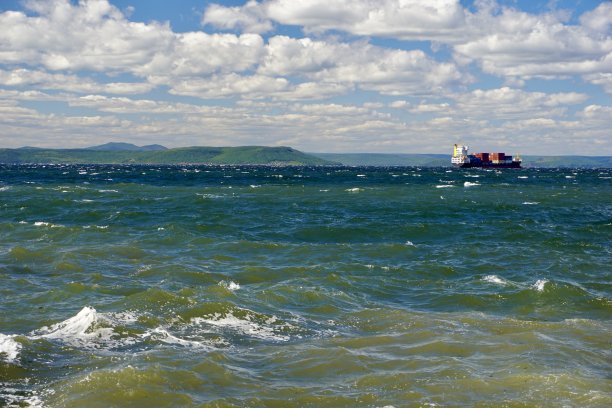 在晴朗的天气里，波涛汹涌的大海。湛蓝的天空上有云，海上有船只和帆板运动员。海上的风。风帆冲浪者在湛蓝的天空下乘风破浪。图片下载