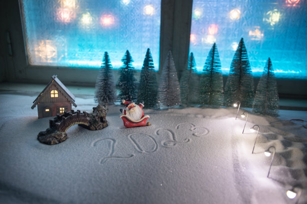 圣诞和新年的迷你房子在雪的夜晚与冷杉树。雪上的小玩具房子，背景上有树和散景城市灯光。圣诞装饰品。节日的概念。图片下载