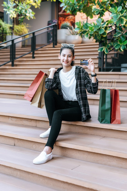 漂亮女人拿着购物袋，坐在楼梯上图片下载