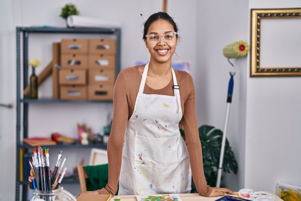年轻的非裔美国女艺术家微笑自信站在艺术工作室图片下载