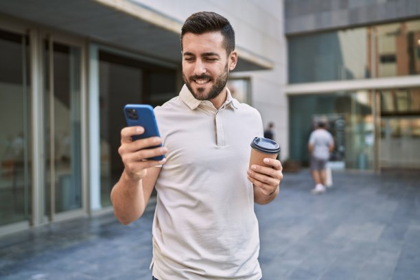 年轻的西班牙男子在街上用智能手机喝咖啡图片下载
