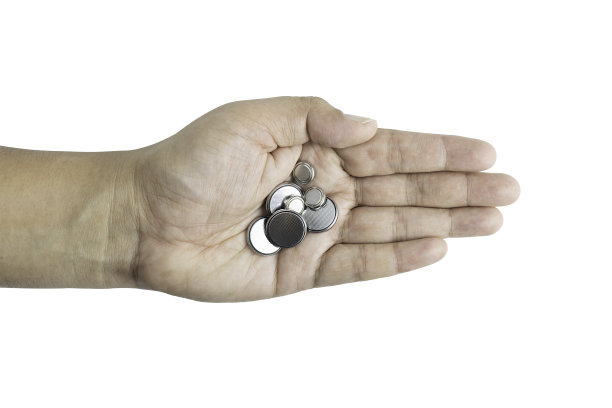 纽扣锂电池在手隔离在白色背景与剪辑路径。图片下载