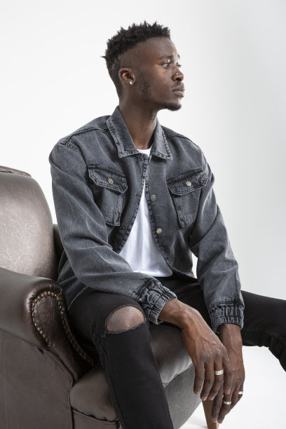 一个非洲裔美国人坐在白色背景的皮革扶手椅上。图片下载