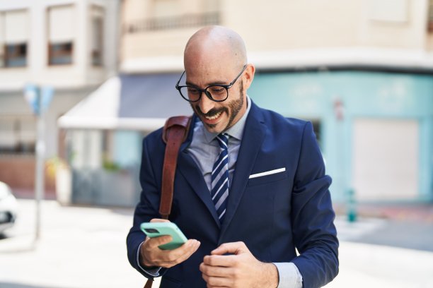 年轻的西班牙裔高管在街上用智能手机微笑自信图片下载