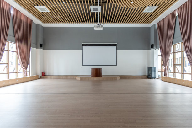 宽敞的教室，空的木质天花板和地板，有一个平台和投影屏幕图片下载