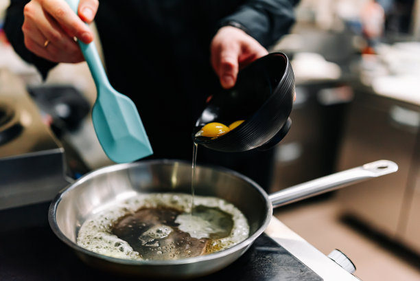 厨师在厨房的煎锅里做美味的炒鸡蛋图片下载