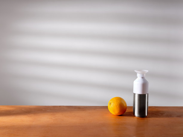 一个瓶子和一个橘子在阳光下放在厨房的柜台上图片下载