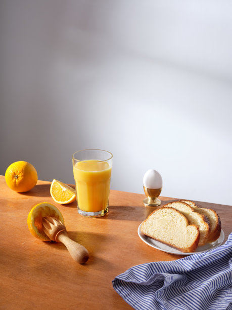 阳光明媚的早餐场景，一杯鲜榨橙汁，一个煮鸡蛋和几片奶油蛋卷面包图片下载