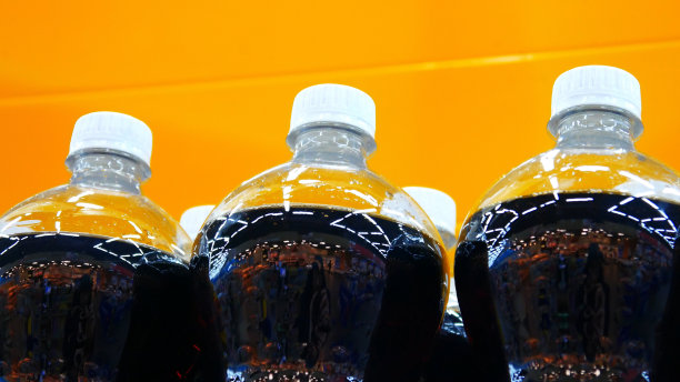 黄色背景下装可乐或其他饮料的塑料瓶特写图片下载