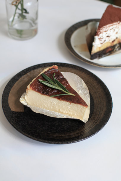 巴斯克芝士蛋糕和迷迭香放在桌子上的盘子里。美味的自制糕点。节日聚会等。图片下载
