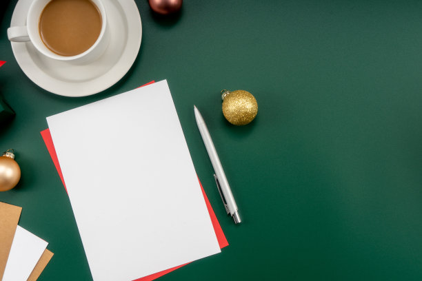 家庭办公室桌子，圣诞装饰品，咖啡杯，键盘，纸质笔记本。圣诞节的工作区。图片下载