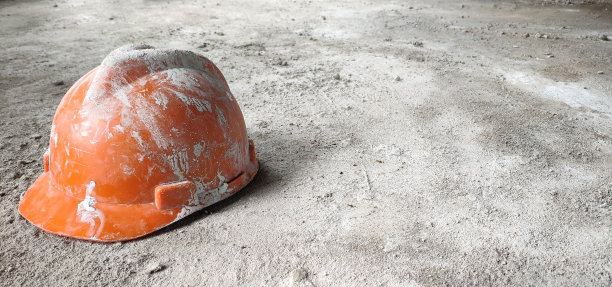 背景是建筑工地工人留在混凝土地板上的橙色头盔图片下载