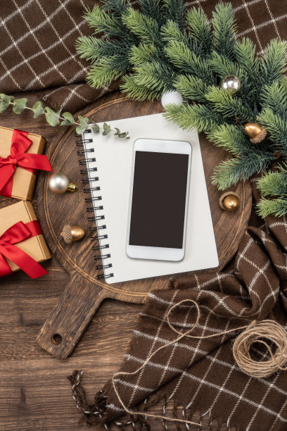 智能手机和笔记本上的木制砧板与圣诞装饰。图片下载