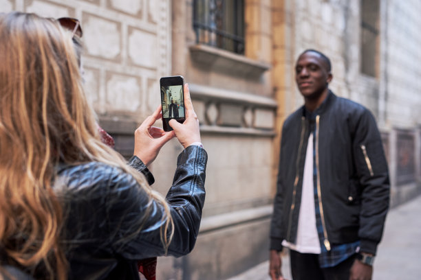 女朋友在街上拍她男朋友的照片。图片下载