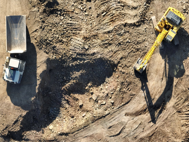 工业矿山挖掘机正在施工现场挖土，装载卡车。无人机俯视图。图片下载