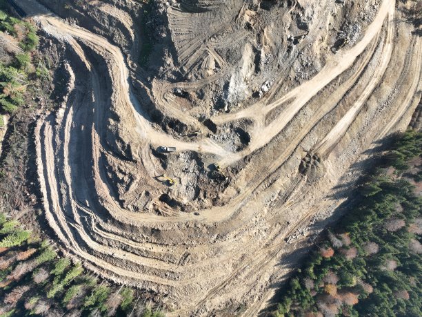 工业矿山挖掘机正在施工现场挖土，装载卡车。无人机俯视图。图片下载