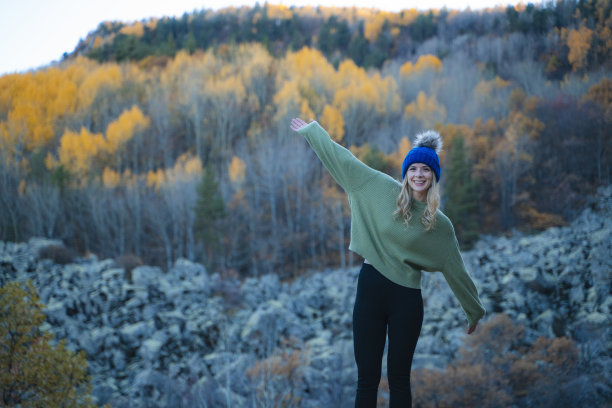 美丽的女人走在秋天的森林里，爬上了山顶。图片下载