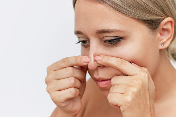 近距离的年轻迷人的金发女子挤压出一个黑色的头或comedoones与她的手指图片下载