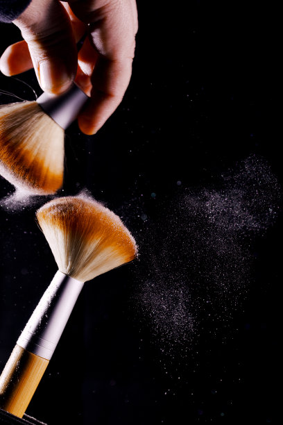 两把化妆刷。黑色背景上的火药云。特写镜头。图片下载