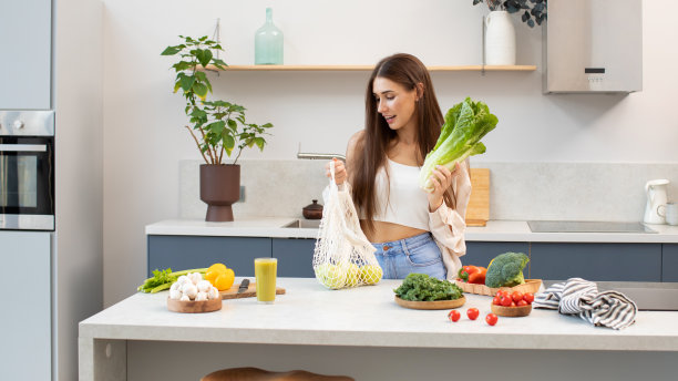 一位迷人的黑发女子会用网眼袋装生菜沙拉。零体重理念，健康生活方式。图片下载
