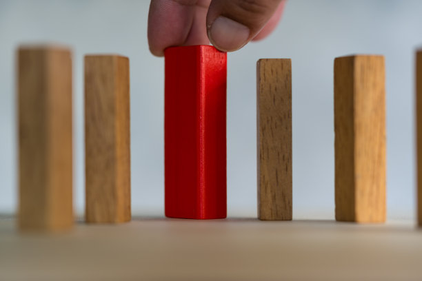 从众多候选人中选择创意人的商业理念又各不相同。近距离用手从许多木块中挑出一块红色木块。图片下载