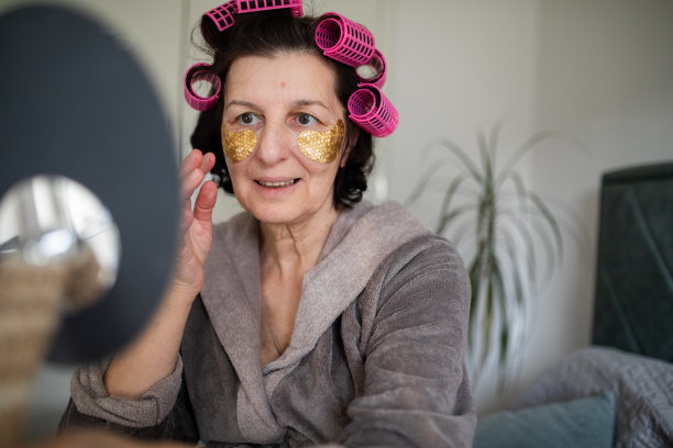 一个戴着眼罩和卷发器的成熟女人在镜子里看着自己图片下载