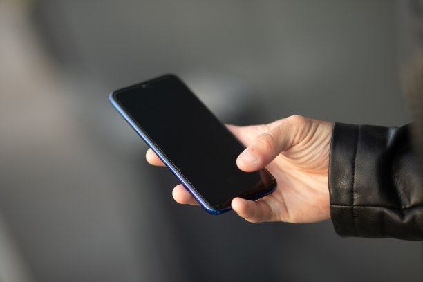 特写镜头的一个年轻的现代男子手持手机，模糊的背景图片下载