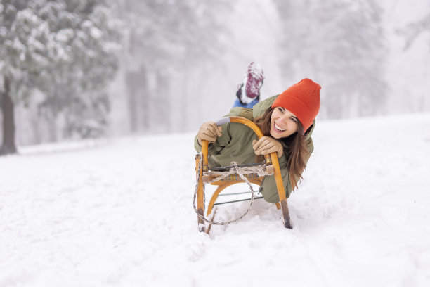 一个女人躺在雪橇上，在雪地里从山上滑下来图片下载