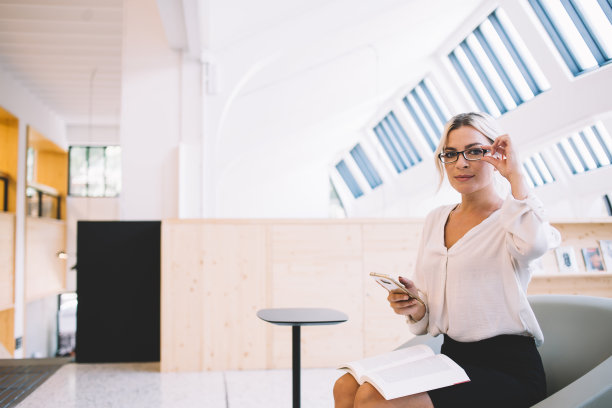智能管理员使用智能手机和调整眼镜在图书馆图片下载