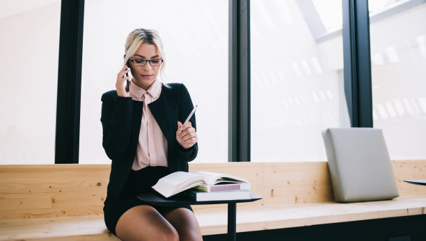 戴光学眼镜的白人企业家做生意，从记事本上查看信息，自豪的女老板使用智能手机应用程序和4g连接与合作伙伴进行移动对话图片下载