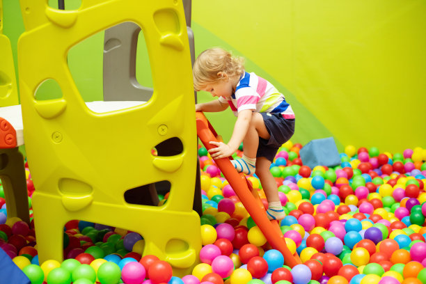 小男孩在室内游乐中心滑滑梯图片下载