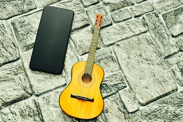 银灰色的砖面上放着手机和木吉他图片下载