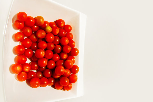 圣女果白色盘子里的圣女果。硬光。明亮的光影。图片下载