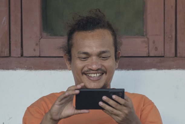 男人在房子前面看智能手机图片下载