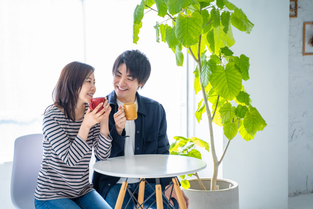 年轻的微笑交谈夫妇喝咖啡在明亮的客厅图片下载