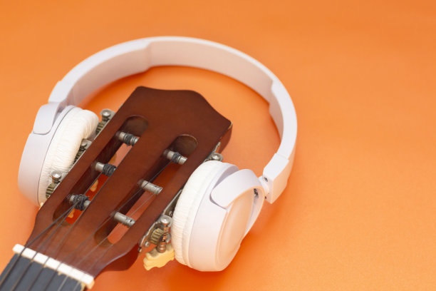 无线耳机在吉他上，橙色背景。音乐理念，听古典音乐图片下载
