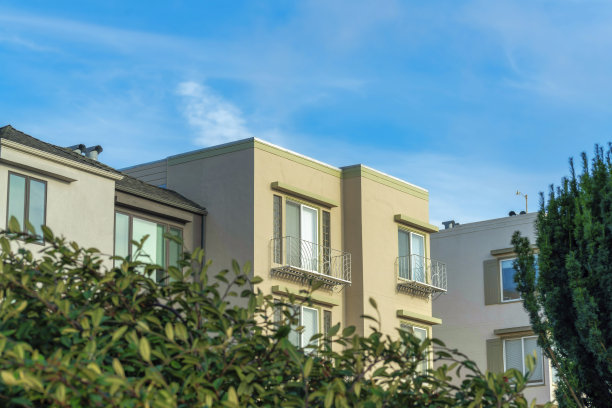 装饰房屋立面米色，橙色和灰色在傍晚的阳光与前院树木图片下载