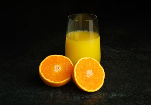 一杯橙汁，在黑暗的背景下，橙汁被分开了一半图片下载