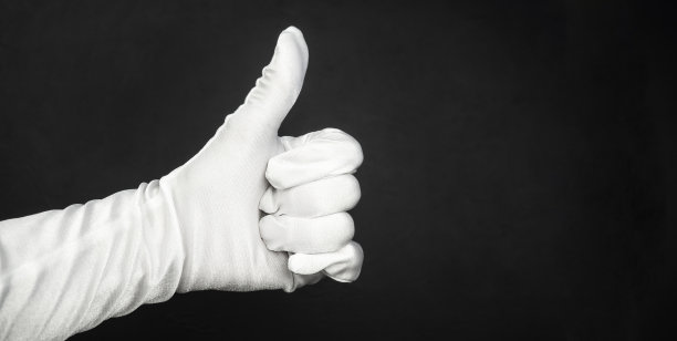 戴手套的手势。在黑色背景上戴上白色手套。手势。图片下载