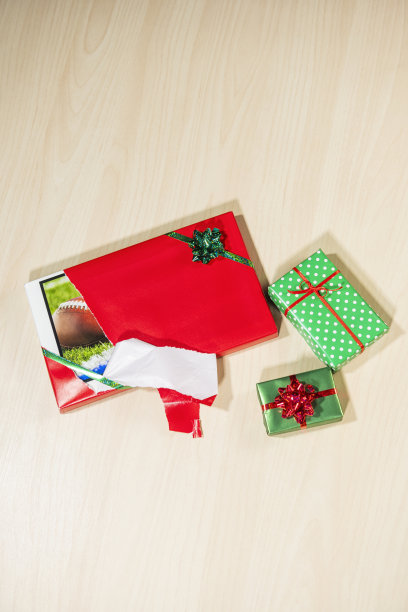 低头看着包装好的大屏幕电视，纸被其他礼物撕破了图片下载