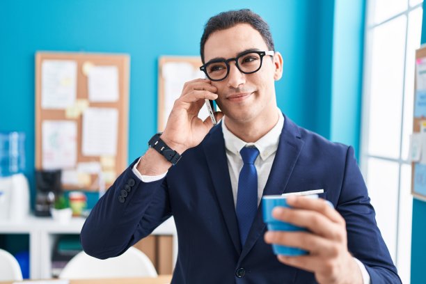 年轻的西班牙裔男子在办公室喝咖啡，用智能手机聊天图片下载